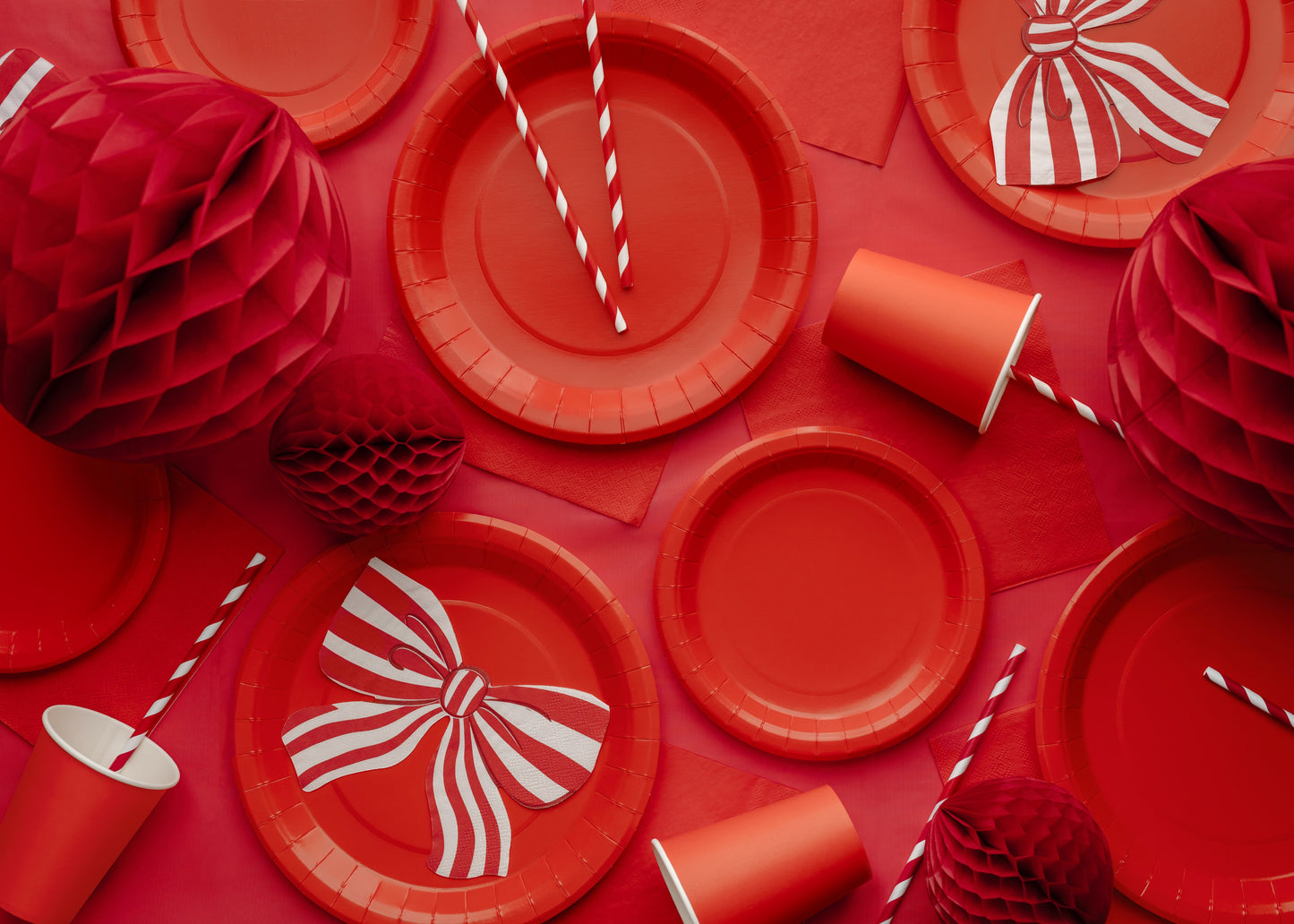 Red party supplies including plates, cups, and decorations on a red background