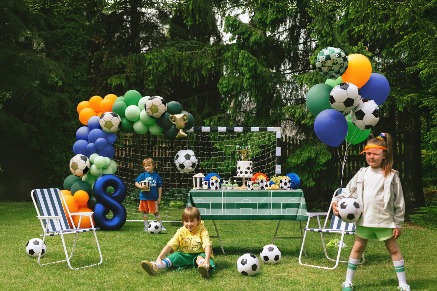 Children playing with soccer balls and balloons in a decorated outdoor setting.