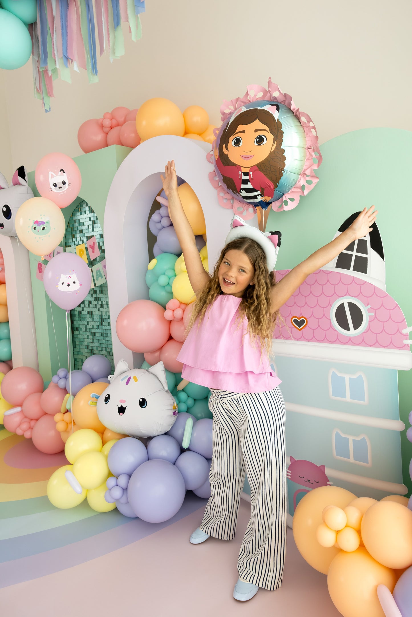 Child posing in front of a colorful balloon arch with cartoon character decorations
