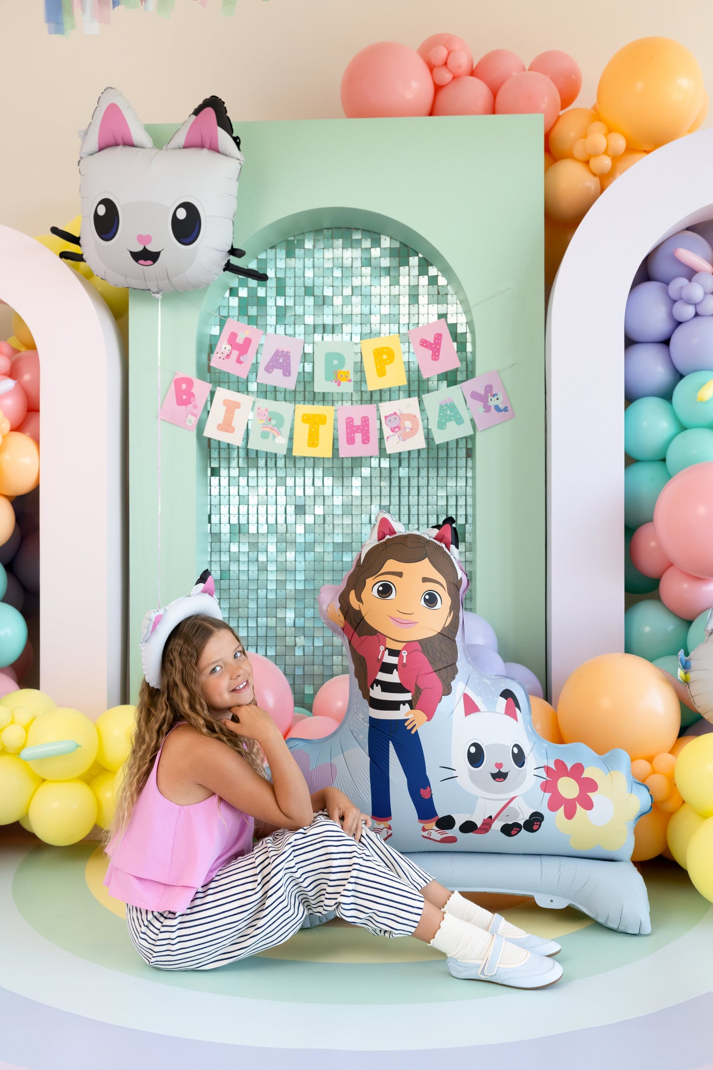 Child sitting in front of a 'Happy Birthday' sign with Standing Gabby Foil Balloon and colorful balloons.