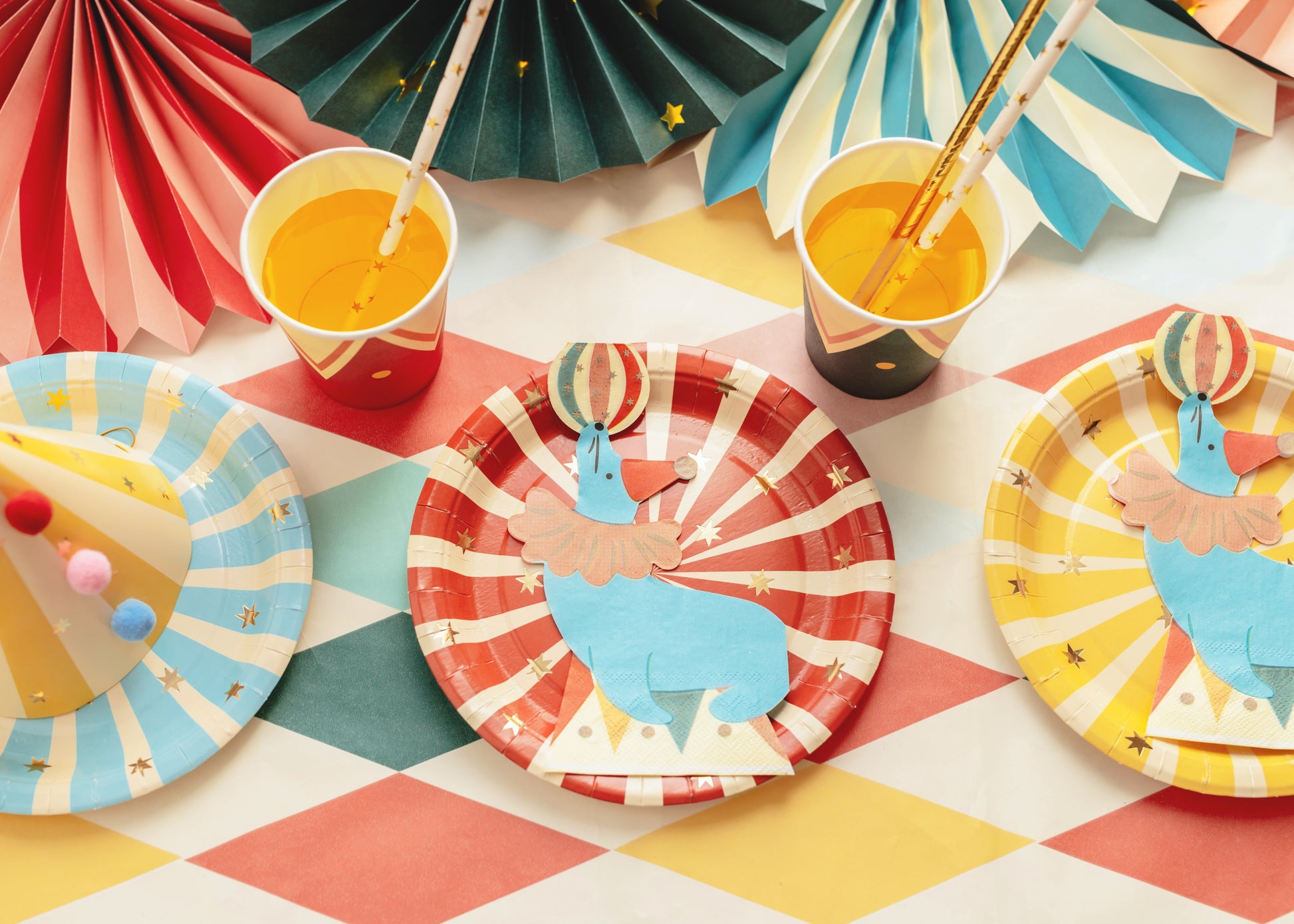 Colorful paper plates with animal designs on a patterned tablecloth.