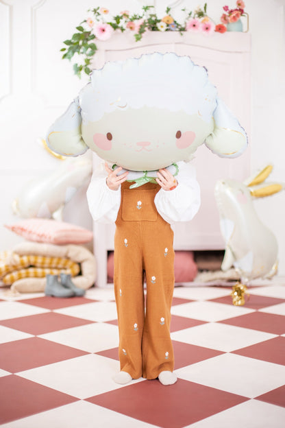 Child holding a large sheep foil balloon, playful and soft pastel room decor