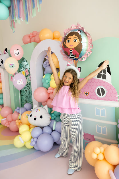 Child posing in front of a colorful balloon arch with cartoon character decorations