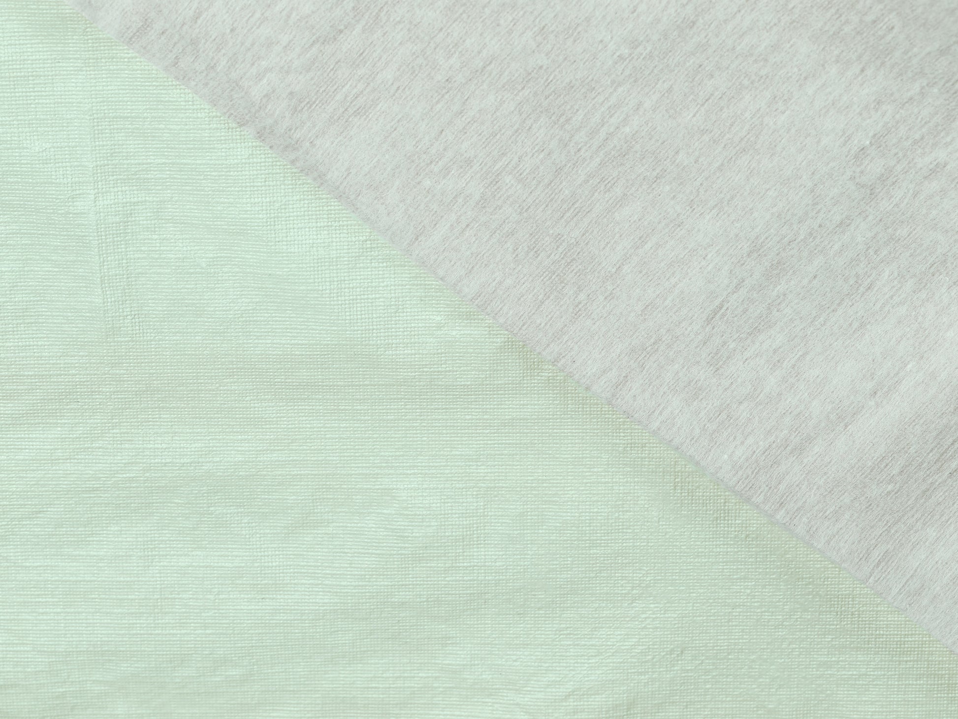 Close-up of a fabric with a diagonal pattern transitioning from light green to white.