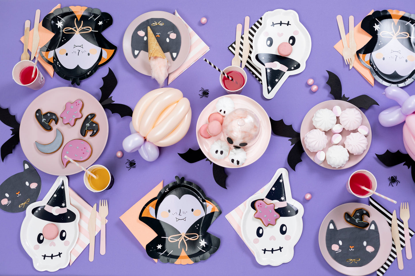 Halloween-themed paper plates, napkins, and cutlery on a purple background