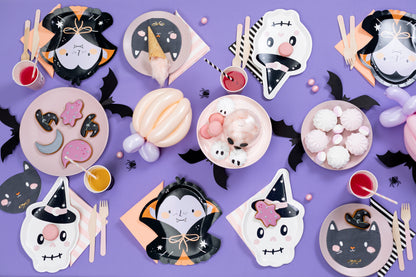 Halloween-themed paper plates, napkins, and cutlery on a purple background