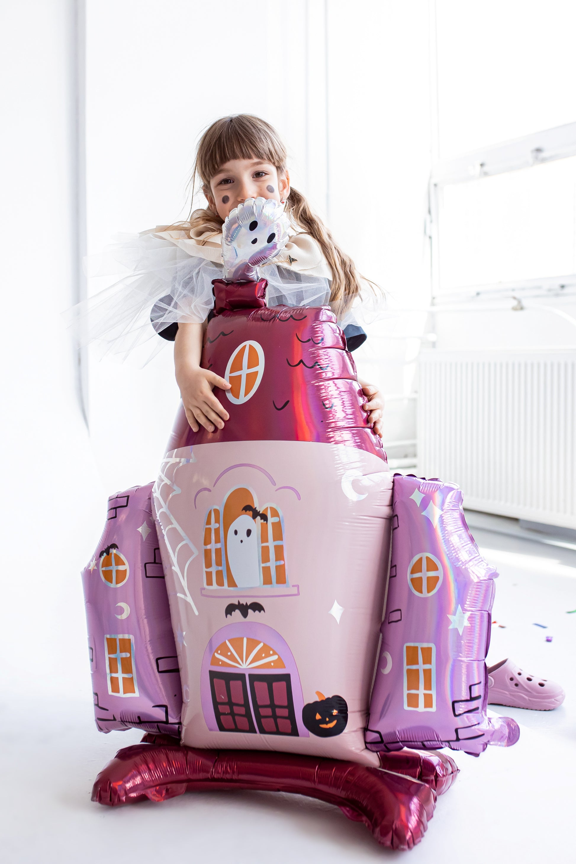 Child holding a haunted house foil balloon