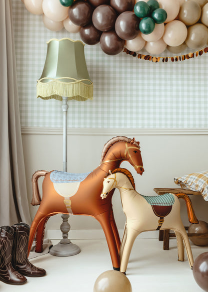 Inflatable horse balloons for kids' birthday party with rustic Western decor and cowboy boots