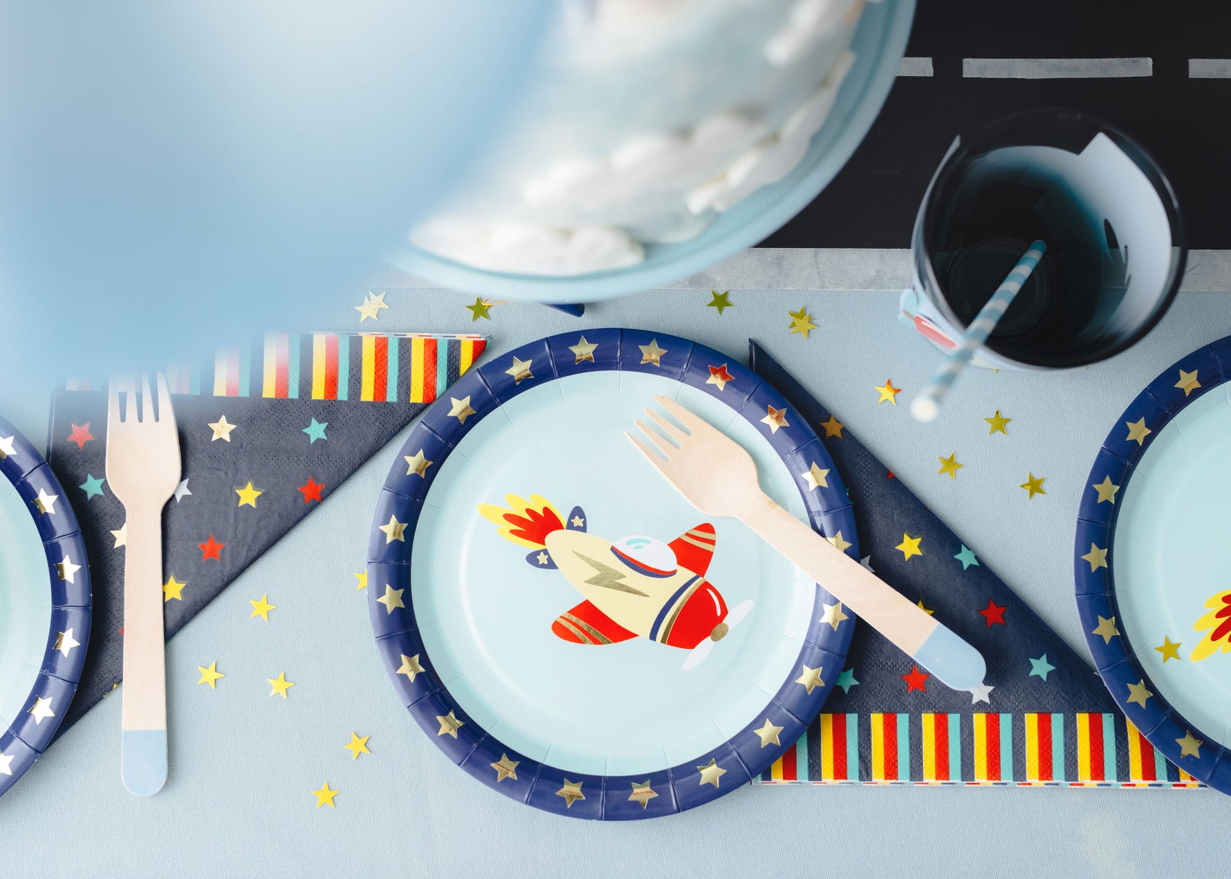 Party table setting with plane-themed plates, wooden cutlery, and napkins