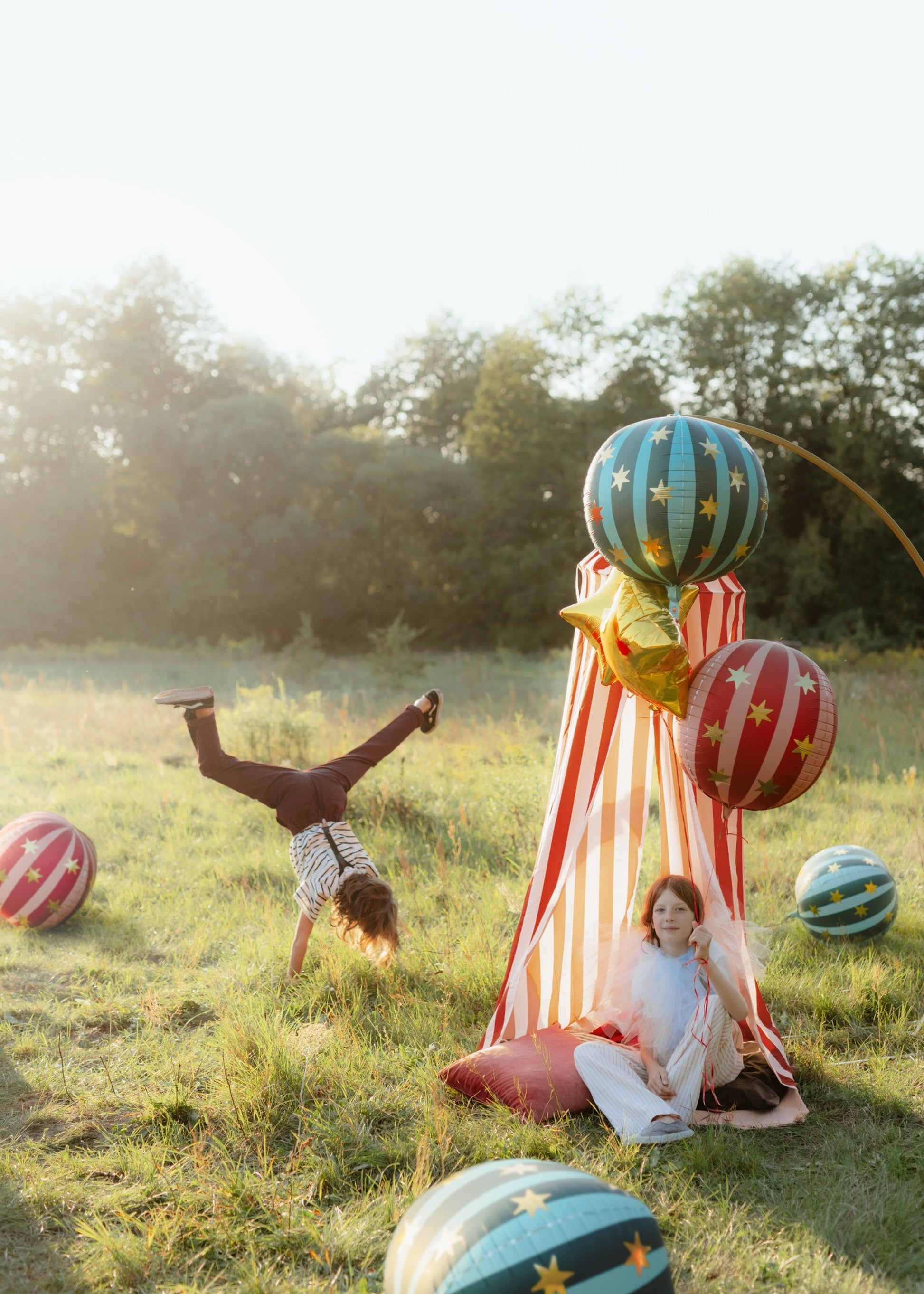 Round green and red foil balloon with vertical turquoise stripes and decorated with golden stars