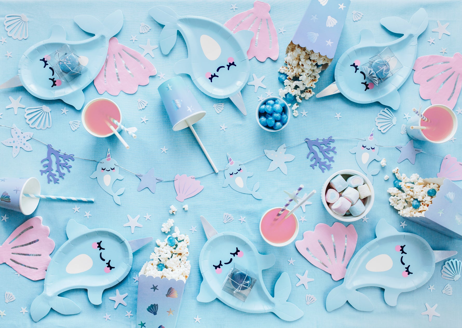 Party table setup with mermaid-themed plates, cups, and decorations