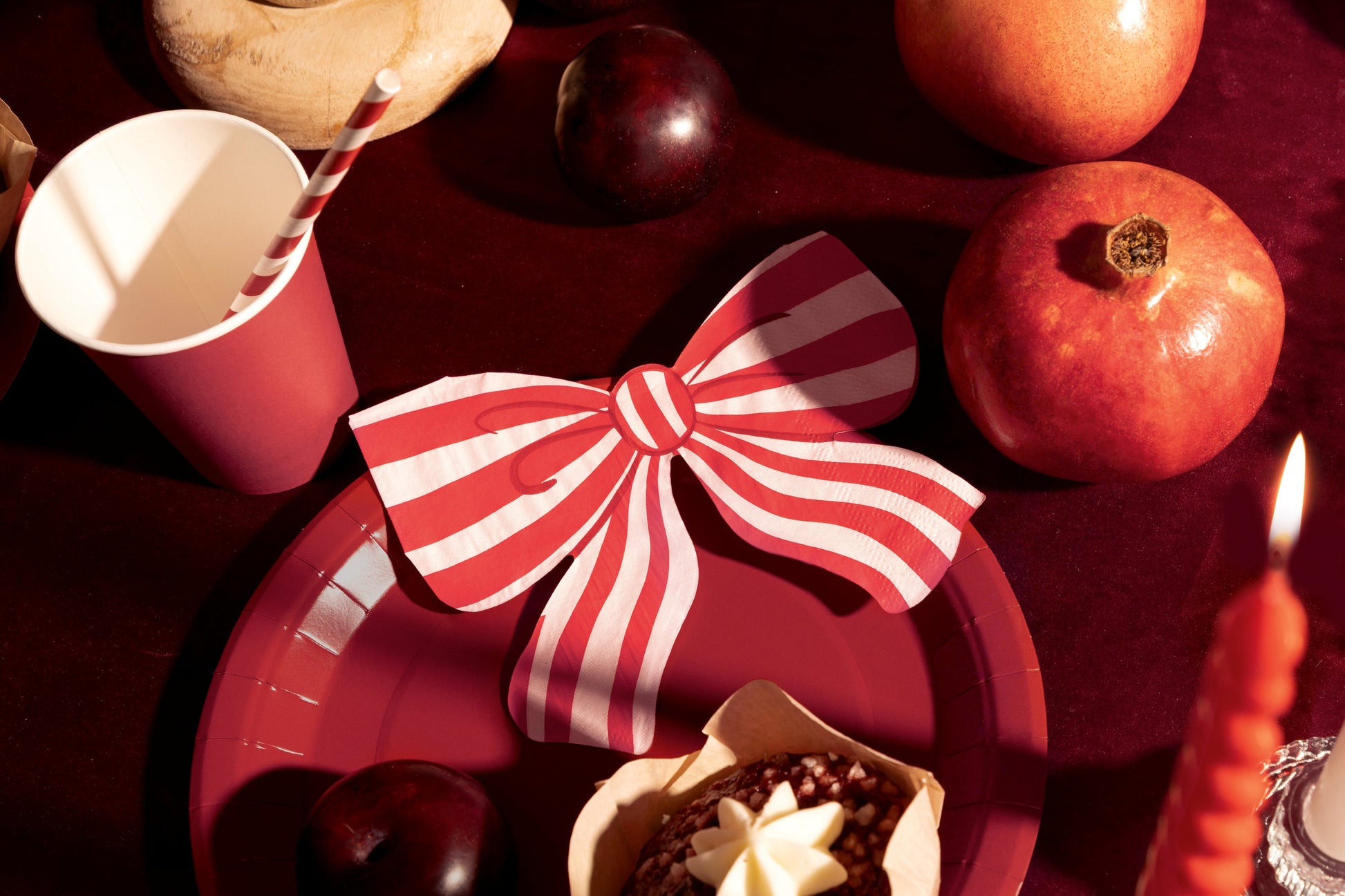 Red plate with a white bow, red cup, and apples on a dark surface