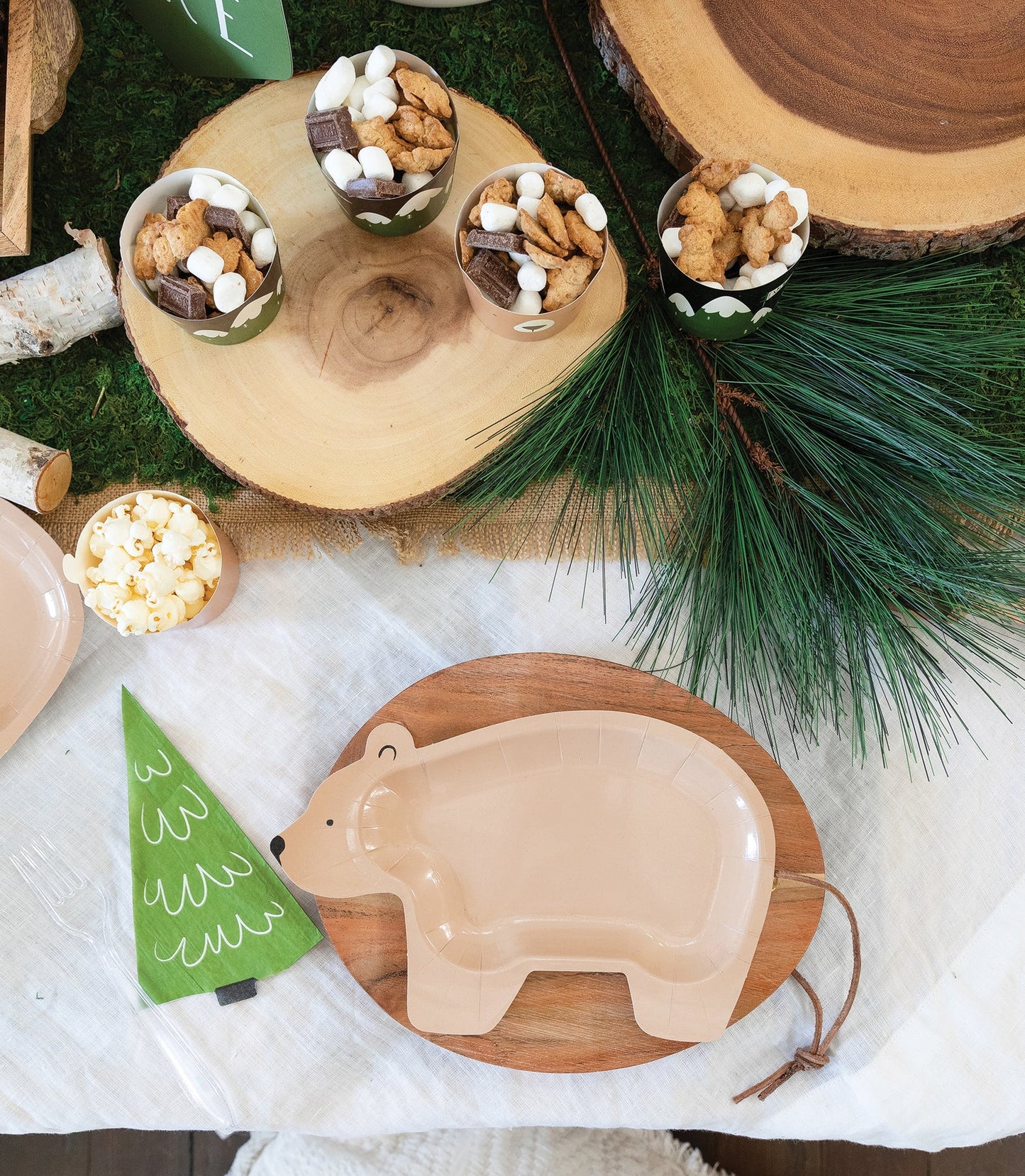 Decorative setting with a bear plate, small tree, and food items on a wooden surface.