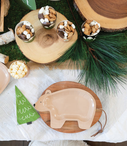 Decorative setting with a bear plate, small tree, and food items on a wooden surface.