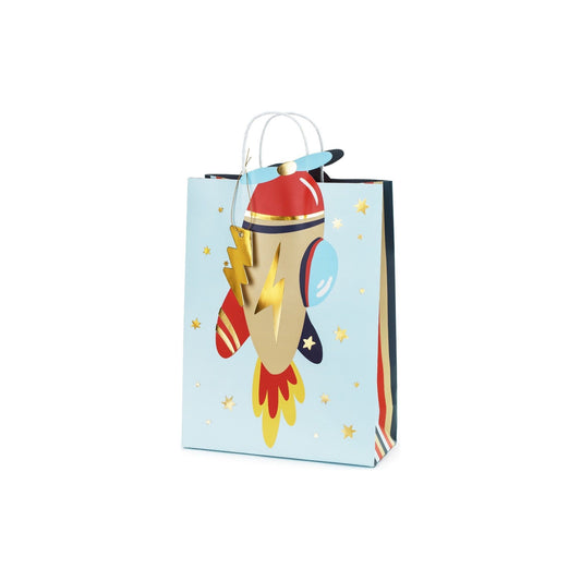 Paper gift bag decorated with a rocket illustration, golden lightning bolts, and a string handle.
