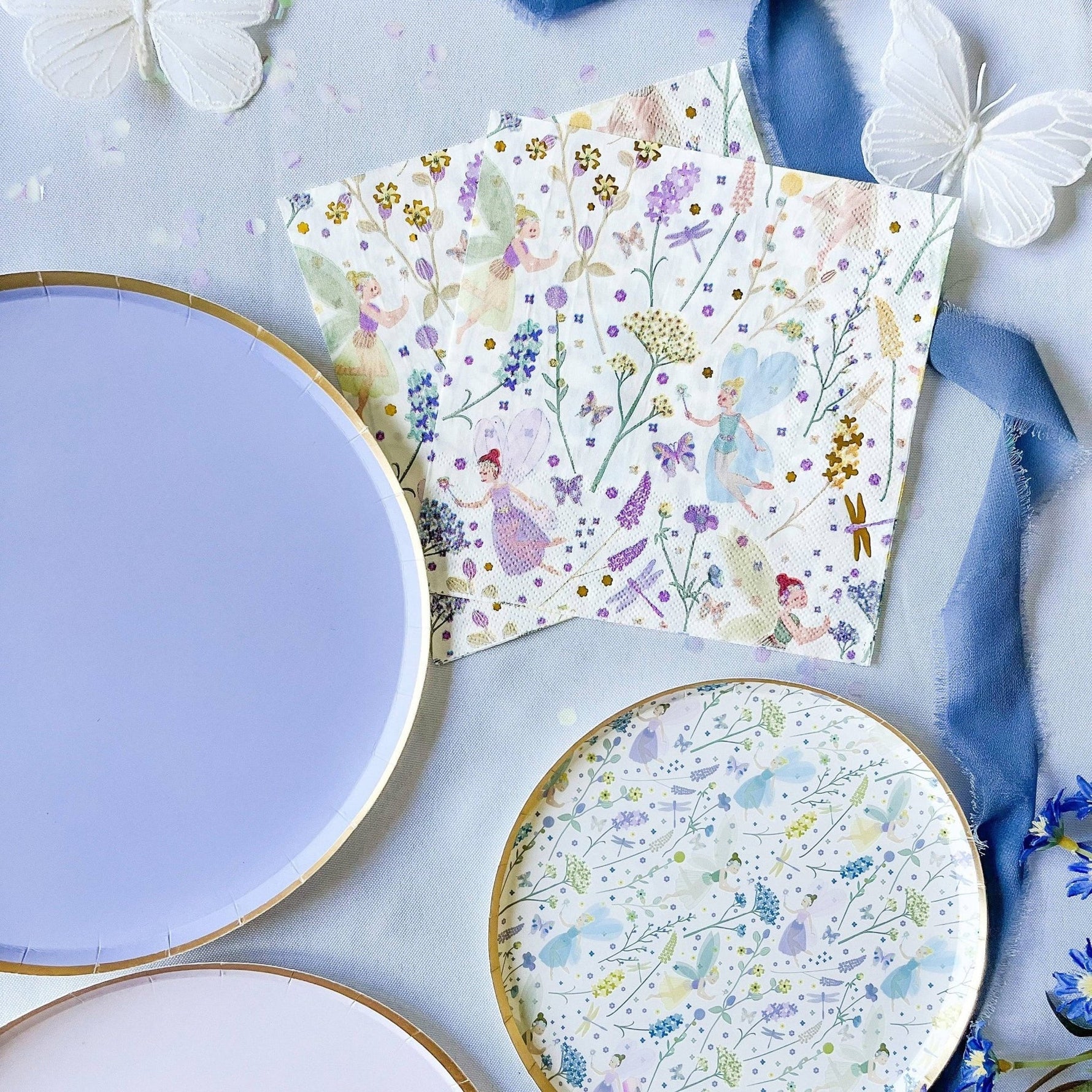 Floral-patterned paper plates on a light blue surface with decorative elements.